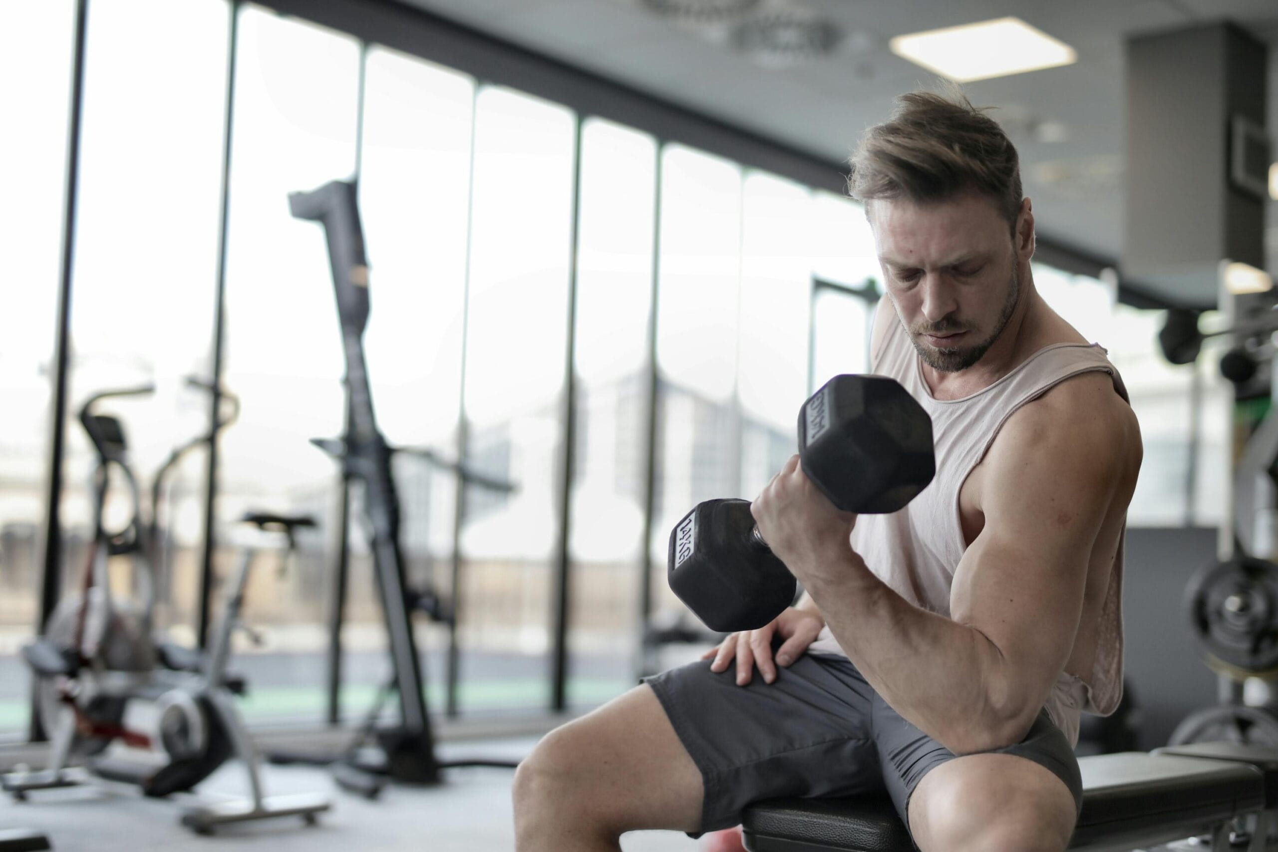 Focused man working out with a dumbbell in a well-equipped gym for strength training.